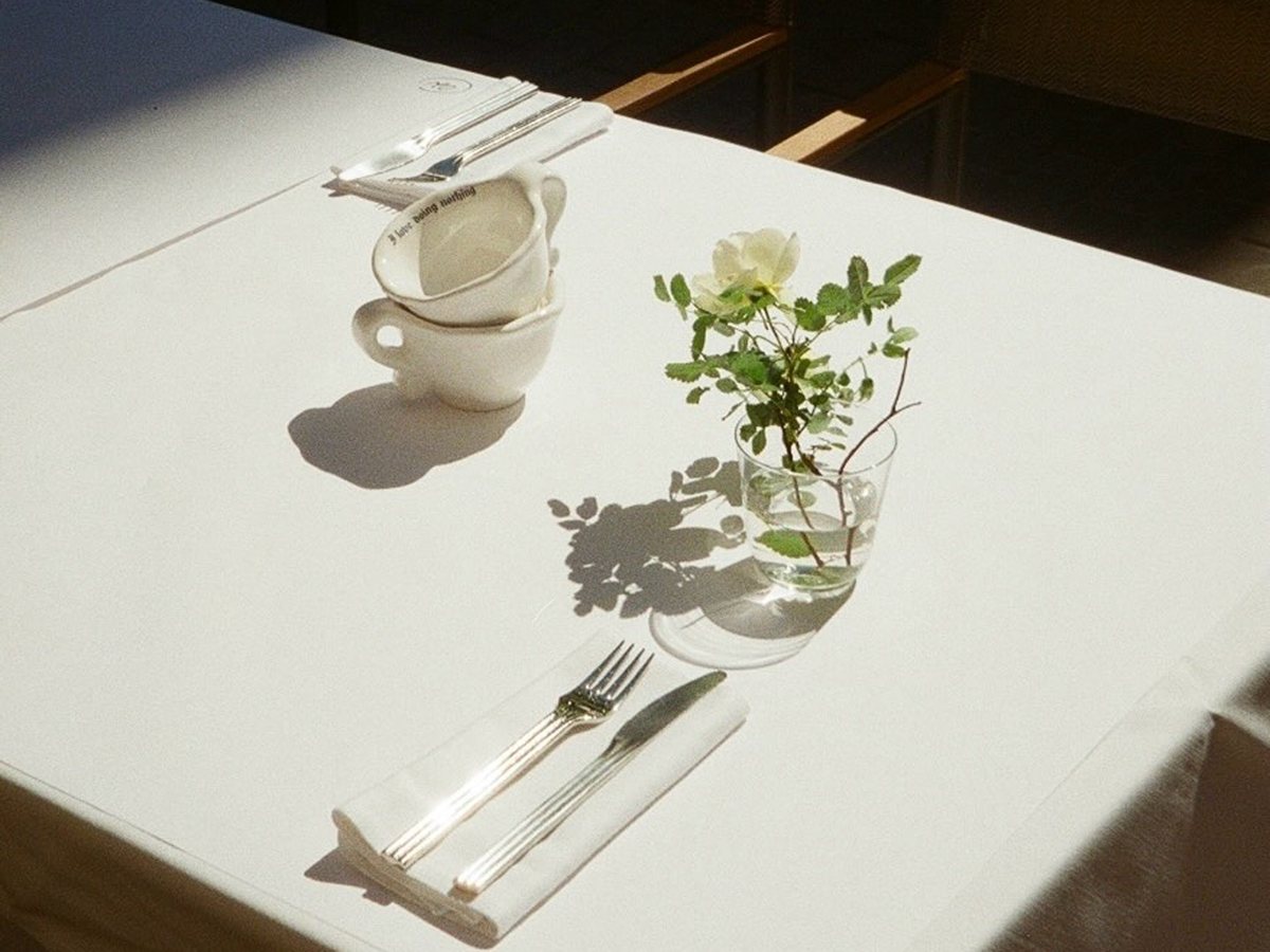 YolkHaus table in Riga with cups and a flower in the sun